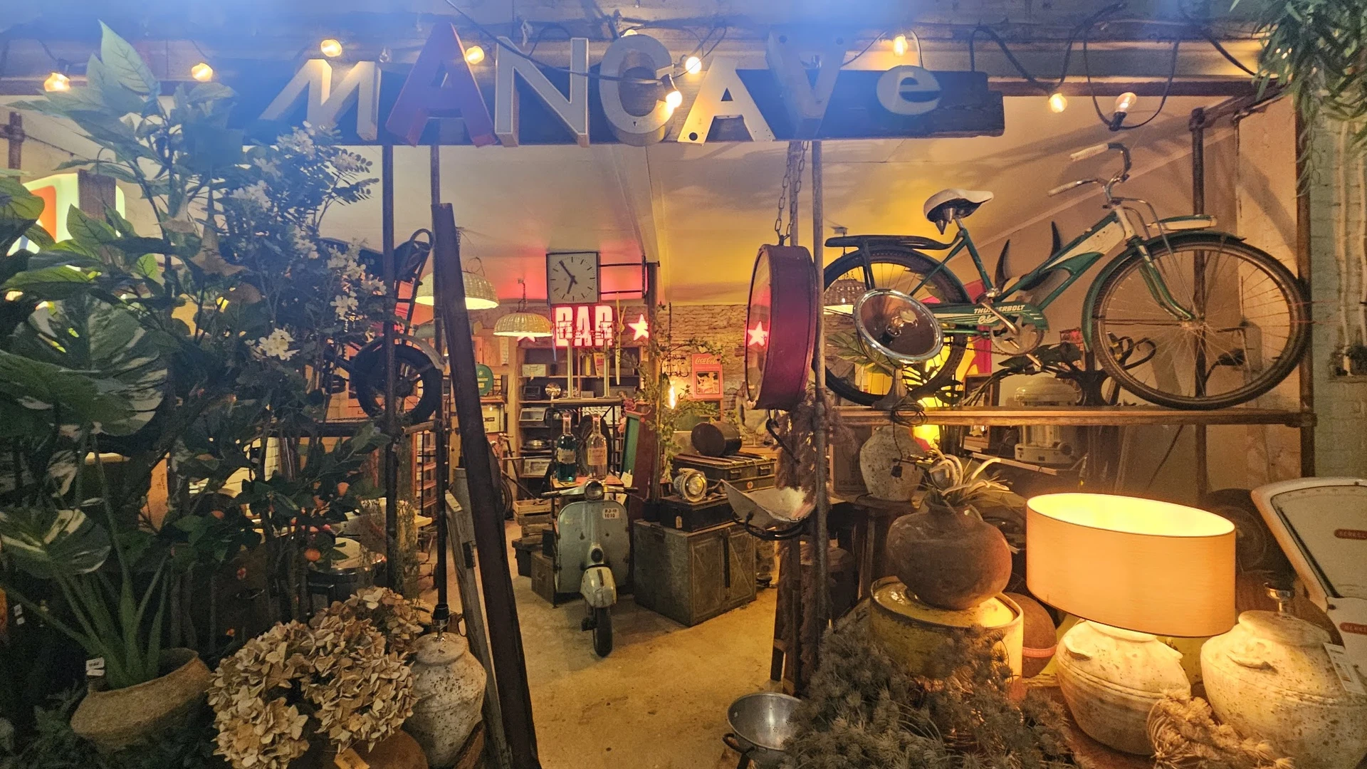 Vintage winkelinterieur met fietsen, lampen, meubels en decoratieve objecten onder warme gele verlichting