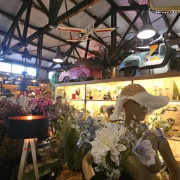 Winkelinterieur met vintage scooters aan het plafond, bloemendecorstukken, verlichte vitrinekast en industrieel dakframe
