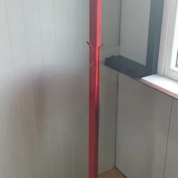 Witte lambrisering en rode pijp in een hoek van een winkelinterieur