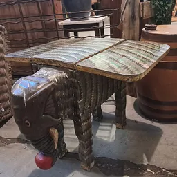 Tweedehands meubels op een terras, onder meer een houten tafel en een bruine ton