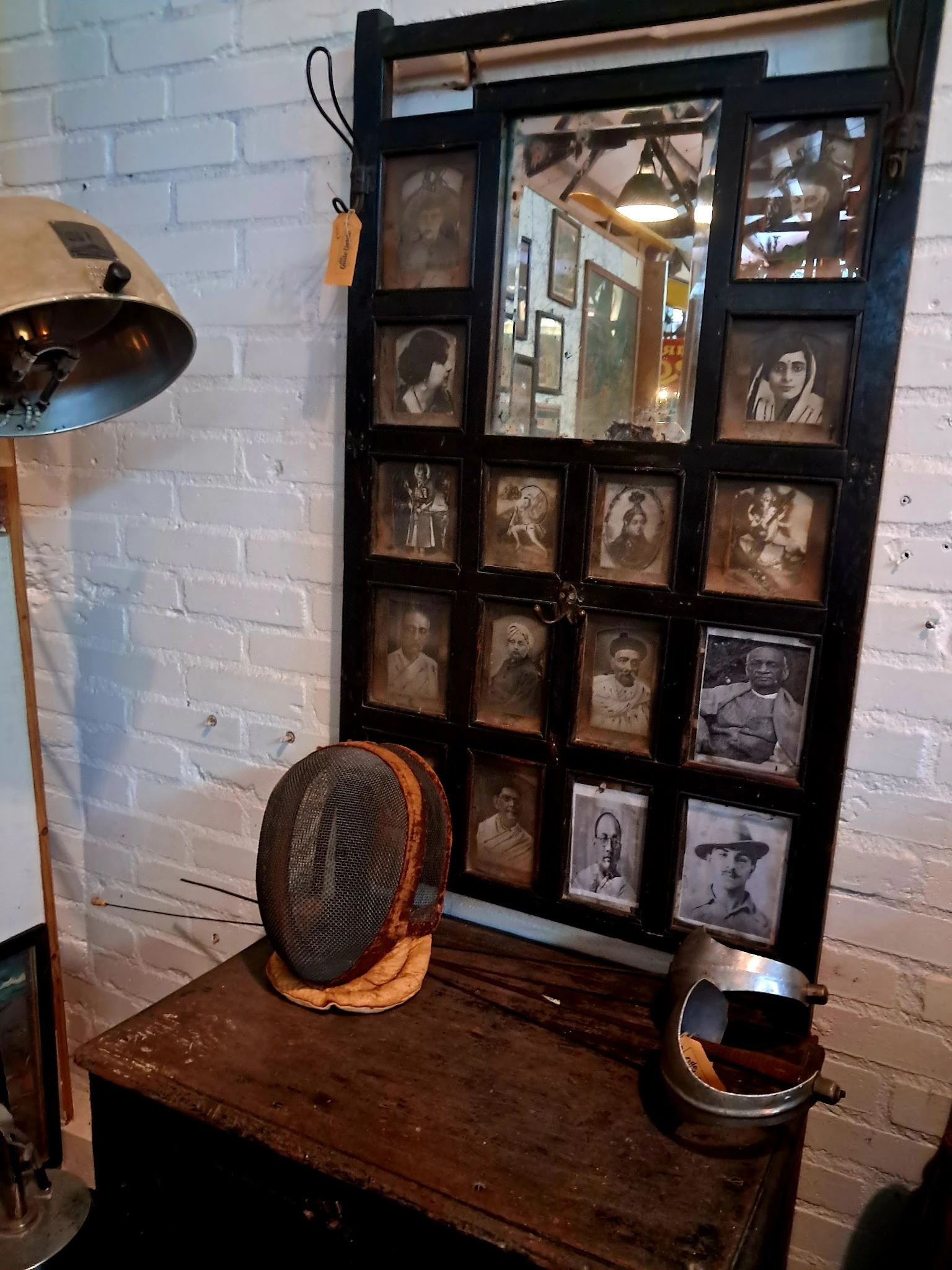 Vitrinekast met vintage en antieke portretfoto's in zwart-wit en sepia, met daarnaast een vintage schermhelm