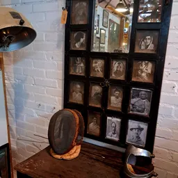 Vitrinekast met vintage en antieke portretfoto's in zwart-wit en sepia, met daarnaast een vintage schermhelm