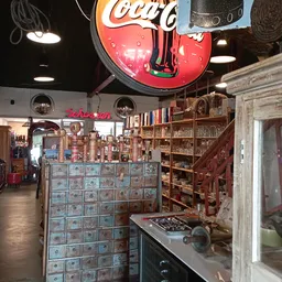 Vintage winkelinterieur met houten stellingen, oude kasten, neonrood gitaarklokkje en boeken in de kringloopwinkel