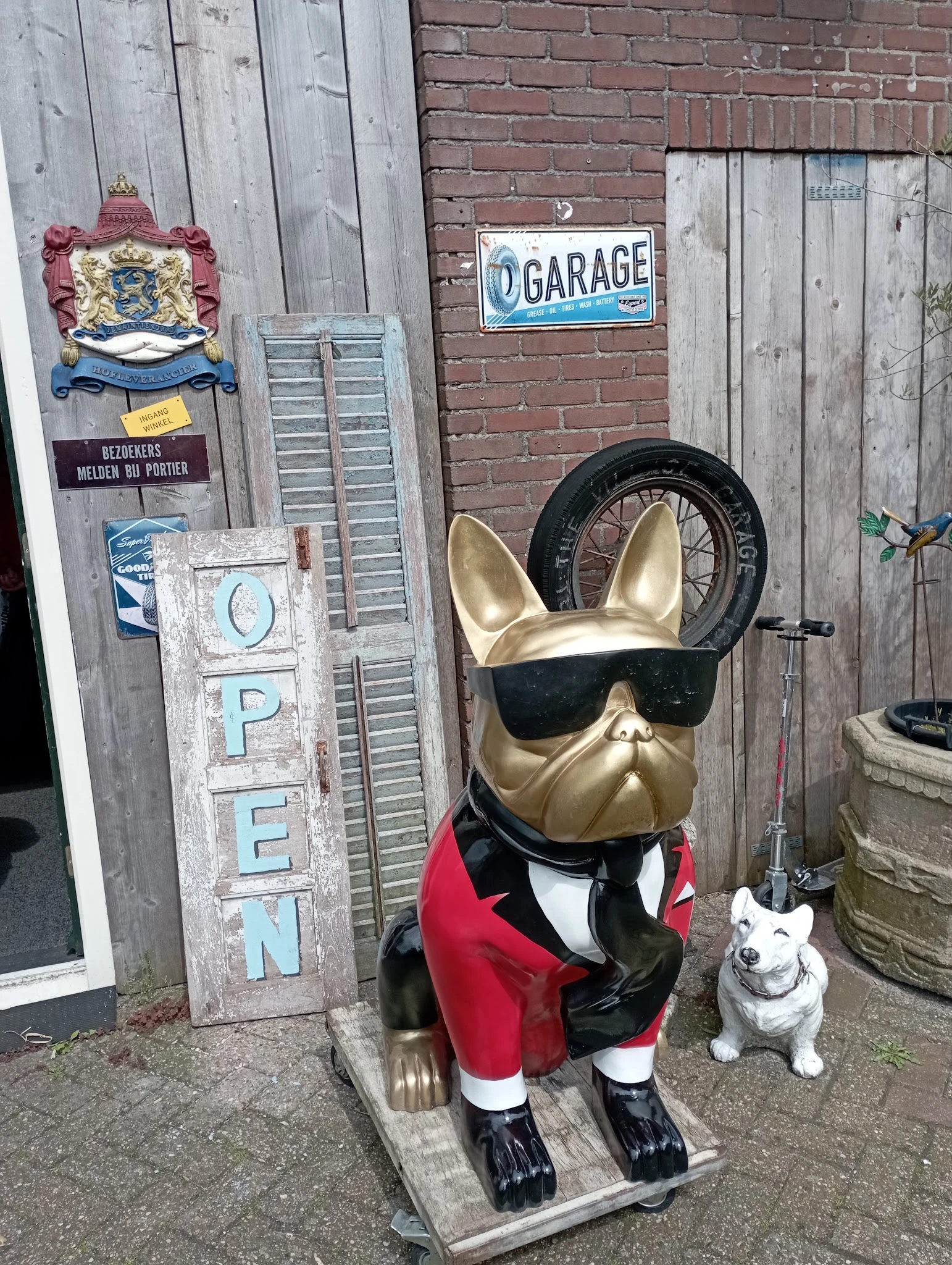 Gouden Franse bulldog-beeldje met zonnebril en rode blazer, een decoratief item in de kringloopwinkel