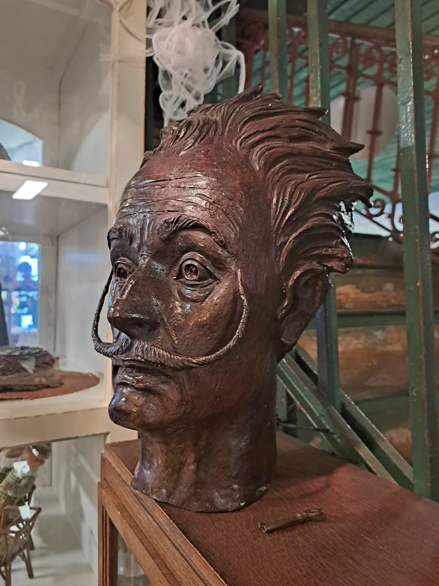 Bronzen sculptuur van een mannenhoofd met krullend haar en snor in museumvitrine