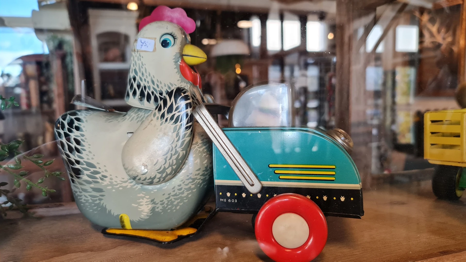 Vintage speelgoed: wit-zwarte kippen-vormige trekauto met roze muts en blauwe aanhanger met rode wielen