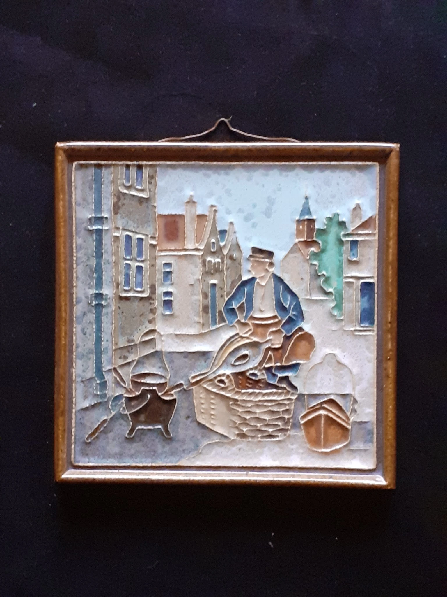 Vintage wandpaneel in reliëf met figuur en middeleeuwse huizen in bruine houten lijst