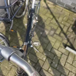 Close-up van een fiets met donkerblauwe frame op stenen ondergrond