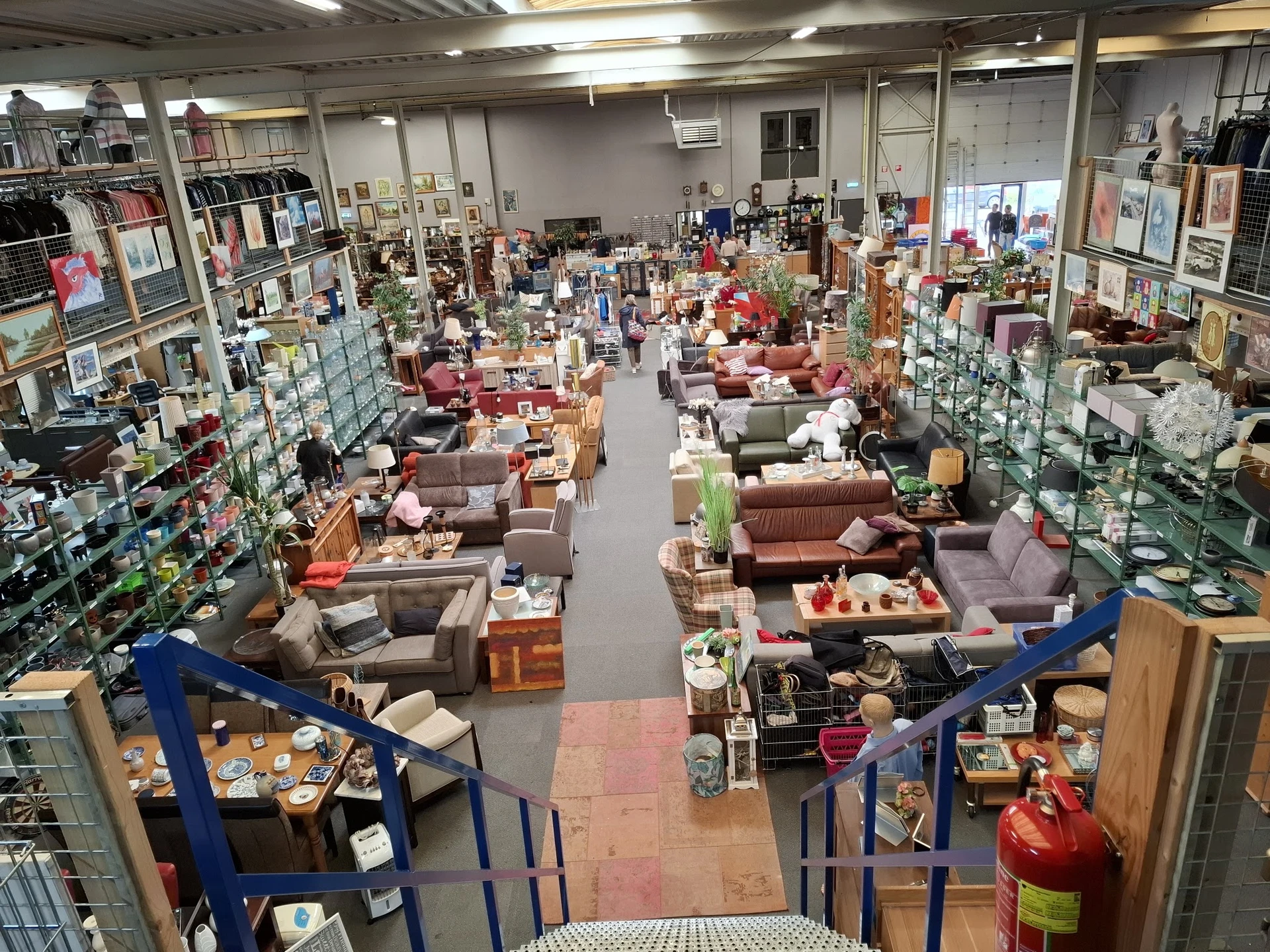 Winkelvloer van kringloopwinkel met veel meubels, stellingen en spullen uitgestald