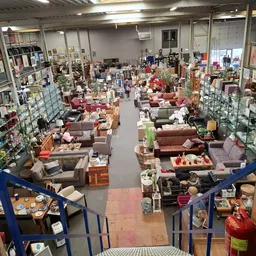 Winkelvloer van kringloopwinkel met veel meubels, stellingen en spullen uitgestald
