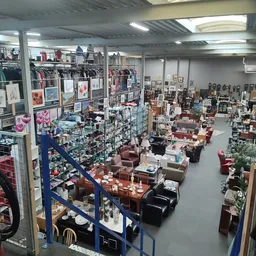 Overzicht van de winkelvloer met meubels, rekken met kleding, kunstwerk aan de muren en diverse spullen uitgestald
