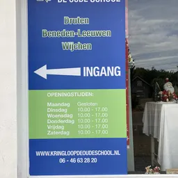 Blauw informatiebord met openingstijden en ingangsrichting van een kringloopwinkel