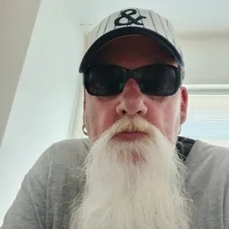 Portretfoto van een man met zonnebril, pet en lange baard