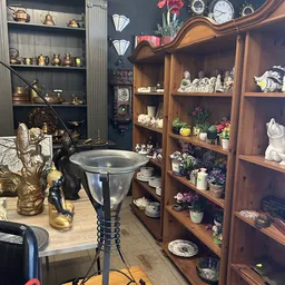 Houten stellingkast met diverse decoratieve artikelen: beeldjes, bloempotten, serviesgoed en collectibles
