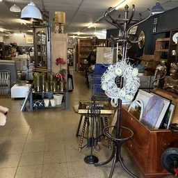 Binnenaanzicht van kringloopwinkel met diverse meubels, huishoudartikelen en decoraties verspreid over de winkelruimte