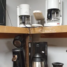 Plank met tweedehands keukenapparaten: koffiezetapparaten, koptelefoon en andere huishoudelijke apparaten