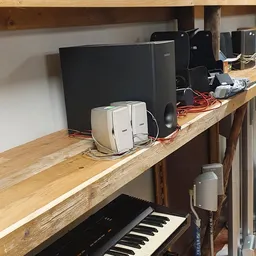 Houten werkblad met computerrandapparatuur, waaronder speakers, monitors en kabels