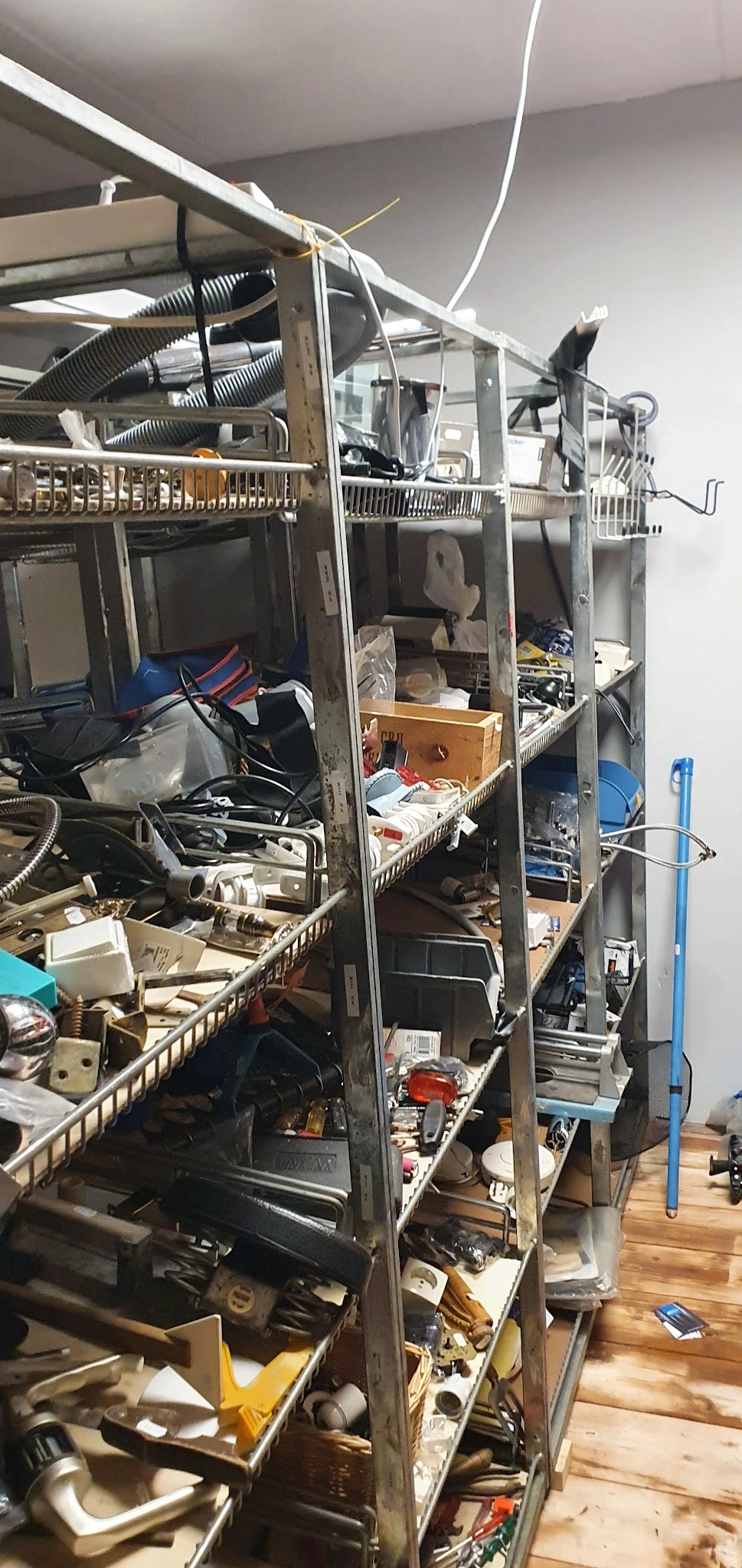 Overvol rek in kringloopwinkel met diverse gebruikte spullen, dozen en huishoudartikelen