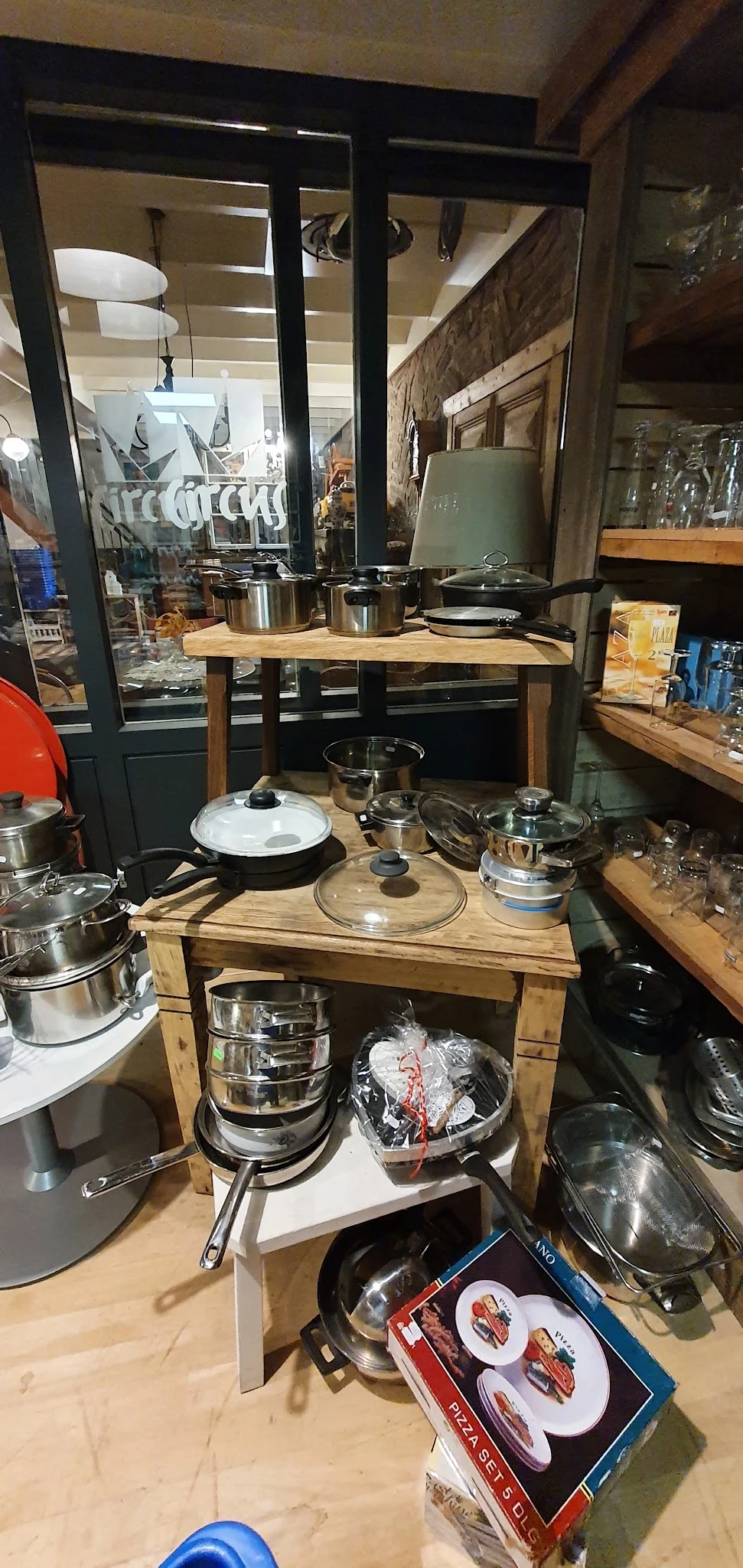 Uitstalling van RVS pannen, kookpotten en keukenspullen op houten tafels in de winkel