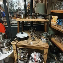 Uitstalling van RVS pannen, kookpotten en keukenspullen op houten tafels in de winkel