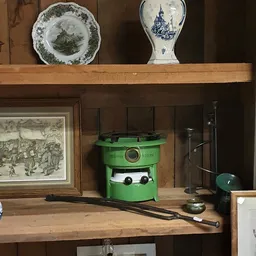 Close-up van een groen vintage apparaat op een houten plank in een vitrinekast