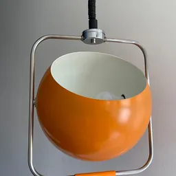 Oranje hanglamp met wit binnenwerk en chromen beugel tegen grijze achtergrond