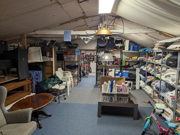 Winkelvloer van kringloopwinkel met stellingen, huisraad, fietsen en diverse tweedehands artikelen