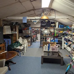 Winkelvloer van kringloopwinkel met stellingen, huisraad, fietsen en diverse tweedehands artikelen