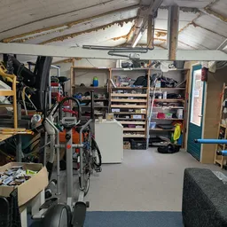 Binnenaanzicht van kringloopwinkel met stellingen, dozen, een fiets en diverse spullen
