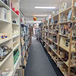Gangpad tussen schappen met diverse tweedehands spullen en decoratieartikelen in de kringloopwinkel