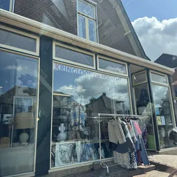 Winkelruit met uithangbord en uitgestalde kleding aan een rek