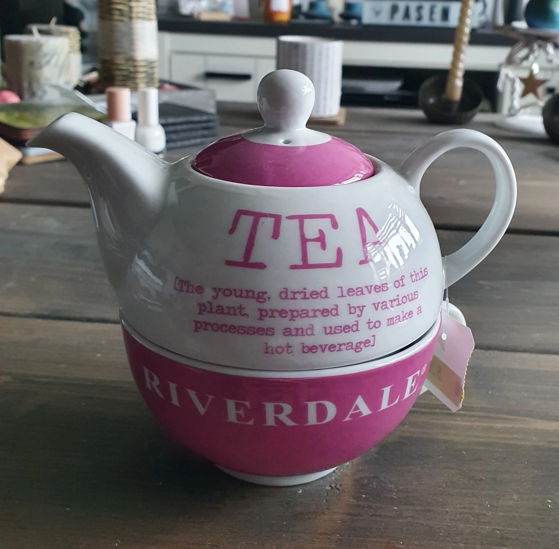 Witte theepot met paarse accenten en TEA-opdruk, met beschrijving van thee