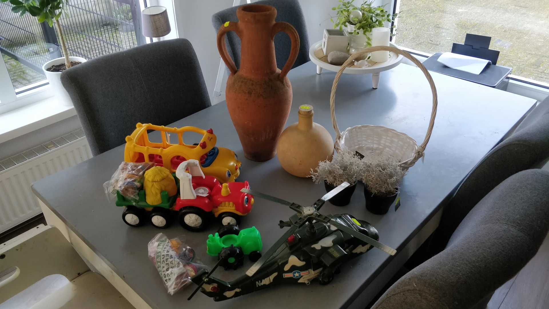 Diverse tweedehands spullen op tafel: speelgoed, aardewerk en decoratieve items