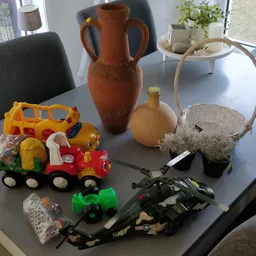 Diverse tweedehands spullen op tafel: speelgoed, aardewerk en decoratieve items