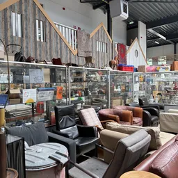 Uitgestalde tweedehands meubels inclusief fauteuils, stoelen en zetels in een kringloopwinkel