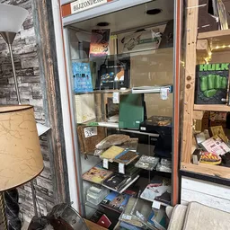 Vitrinekast met tweedehands boeken, dvd's en andere media-artikelen uitgestald op planken