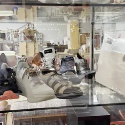 Etalage met uitgestalde tweedehands schoenen en sneakers van verschillende kleuren en merken