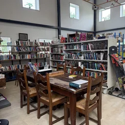 Boekenwinkel interieur met houten tafel en stoelen, omgeven door volle boekenkasten