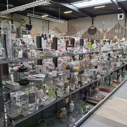 Lange toonbanken vol met glazen vazen, kaarsenhouders en huishoudelijke accessoires in verschillende maten en kleuren