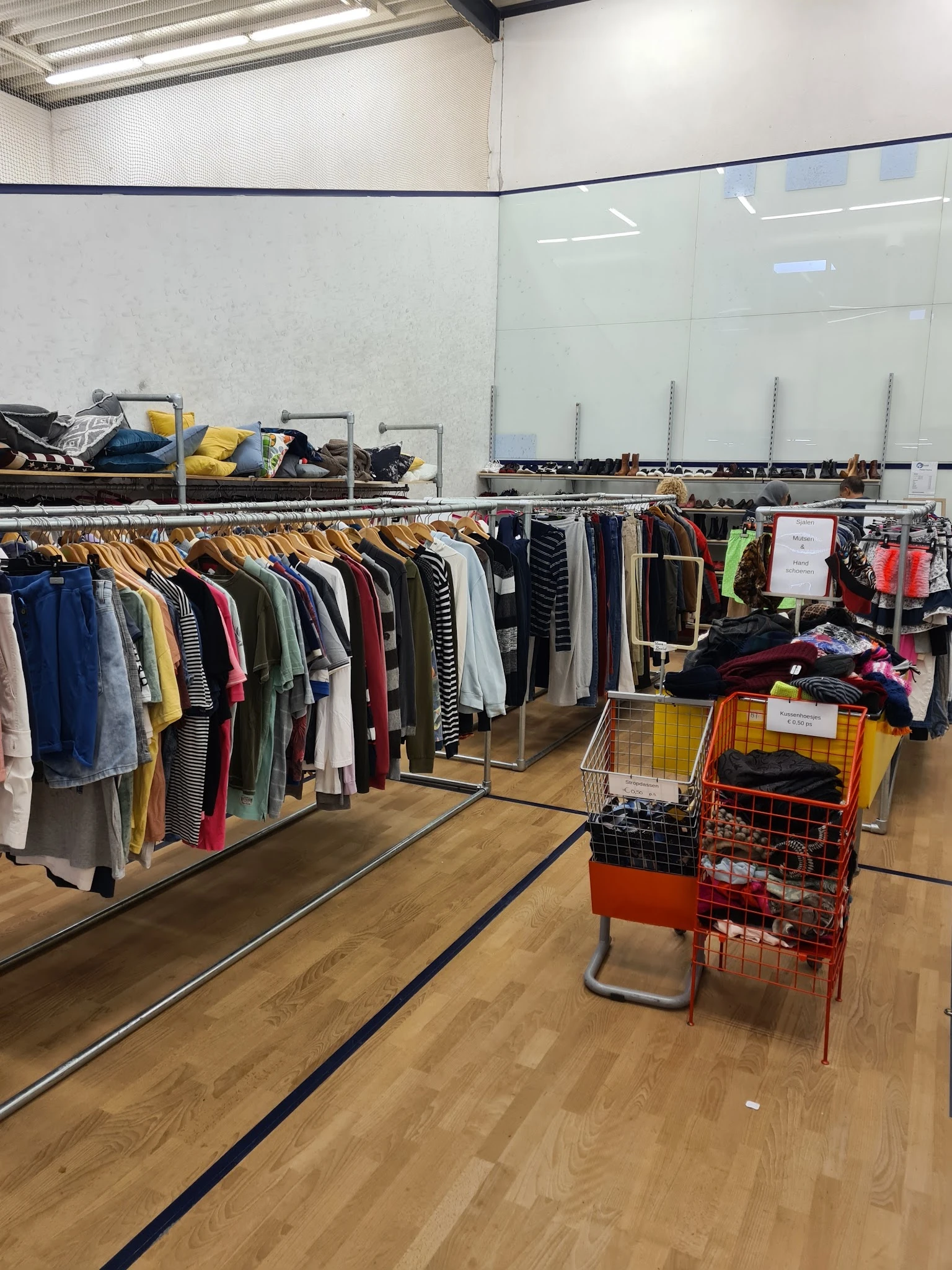 Rekken met tweedehands kleding en winkelwagens met kleding op de kringloopwinkelzolder