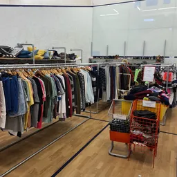 Rekken met tweedehands kleding en winkelwagens met kleding op de kringloopwinkelzolder