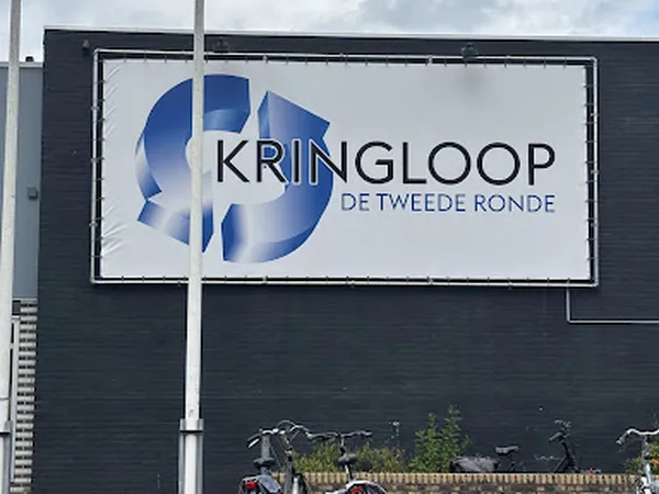 Gevel van kringloopwinkel met groot wit bord met blauw logo en tekst 'KRINGLOOP DE TWEEDE RONDE'