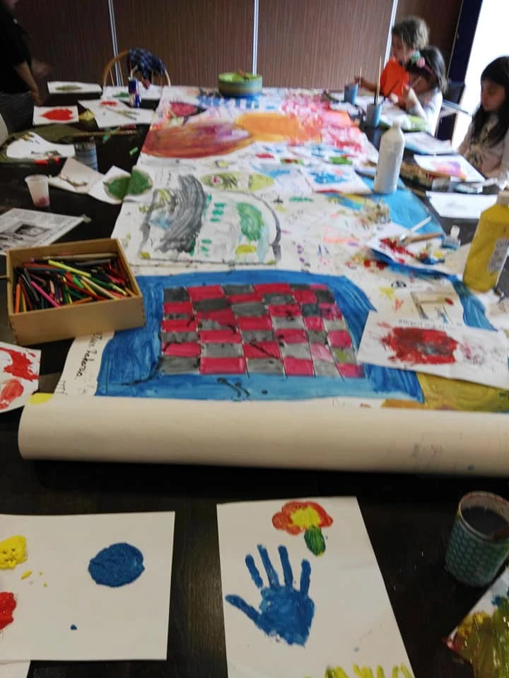 Kindertekeningen en kunstwerkjes op een tafel met kleurkrijt en materialen
