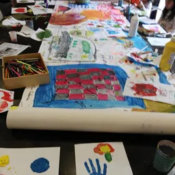 Kindertekeningen en kunstwerkjes op een tafel met kleurkrijt en materialen