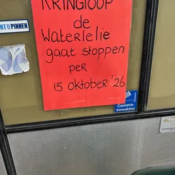 Rood papier met handgeschreven Nederlandse tekst op een winkelruit