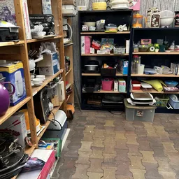 Winkelinterieur met houten en zwarte stellingen vol met huishoudelijke spullen, dozen en servies