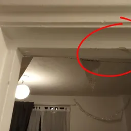 Plafond en muur van een winkelruimte met een lamp en zichtbare schade of vervuiling