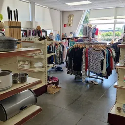 Interieur van kringloopwinkel met kleding op rekken, keukenspullen en huishoudartikelen