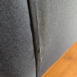Close-up van grijze stofvouw met kleine gaten of beschadigingen in het weefsel