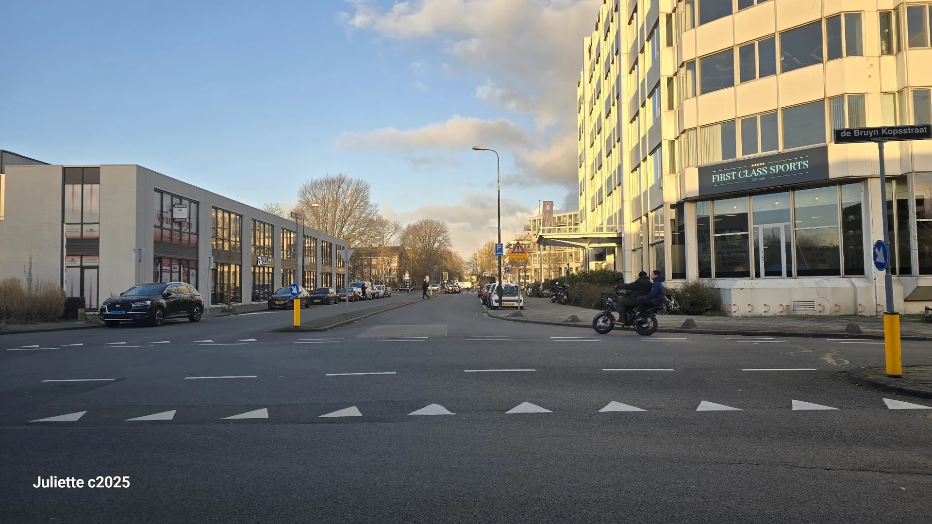 Straatgevel aan De Bruyn Kopsstraat met gele winkelgebouw en 'First Class Sports' winkel aan rechterkant